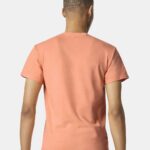 Man standing backwards wearing Gildan Heavy Cotton t-shirt in tangerine color showing off back side