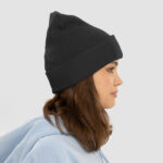 A woman wearing a black classic custom cuffed beanie looking to the side.