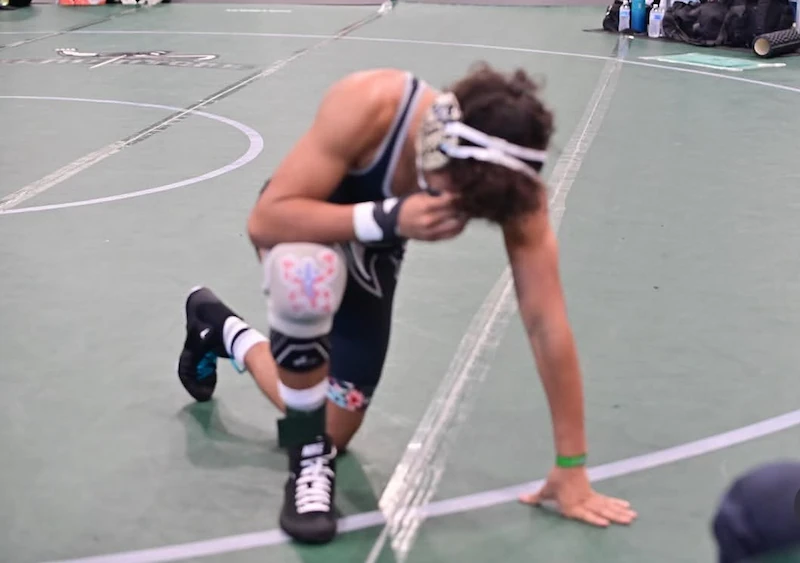 Wrestler wearing a wrestling knee pad while competing on a wrestling mat